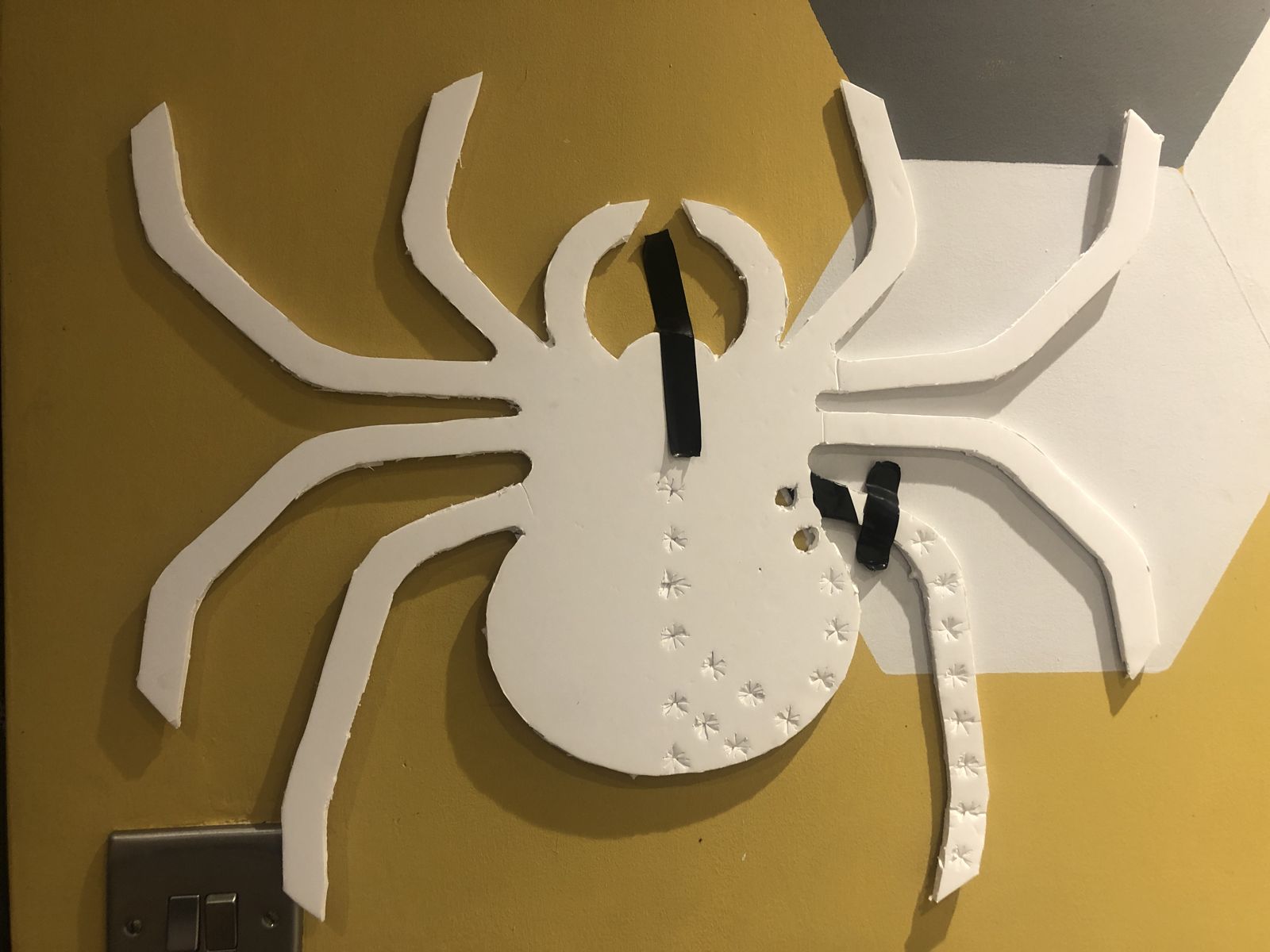 Foam board cut into a spider shape, with the first pixel holes punched along one leg